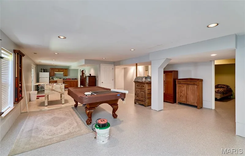 Expansive recreation room featuring recessed lighting, durable flooring, and a dedicated kitchen area with wood cabinetry — 3641 Wind Chime Lane, St Charles, MO 63301