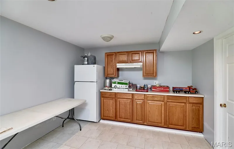 Tile flooring, wood cabinetry with white countertops, recessed lighting, and a neutral wall color — 3641 Wind Chime Lane, St Charles, MO 63301