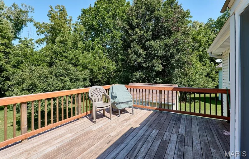 Expansive wood deck with a natural wood railing, surrounded by mature trees — 3641 Wind Chime Lane, St Charles, MO 63301