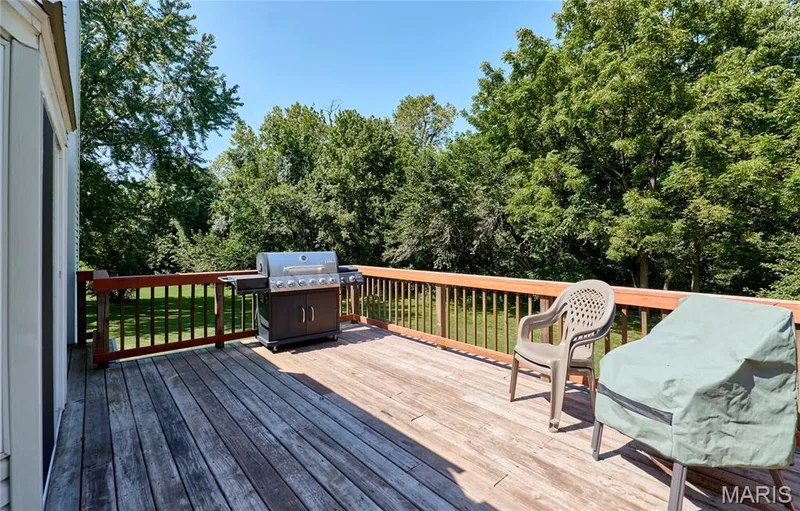 Expansive wood deck with a perimeter wood railing, overlooking a lush, tree-lined landscape — 3641 Wind Chime Lane, St Charles, MO 63301
