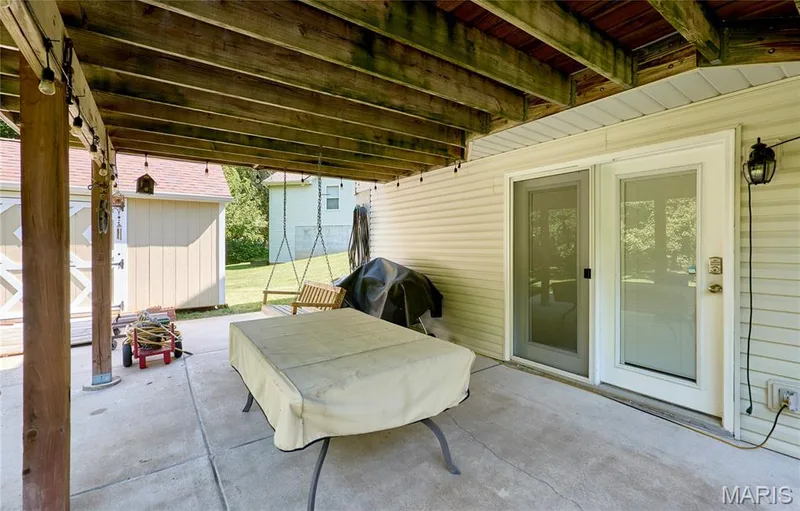 Covered concrete patio with exposed wood beams and white vinyl siding — 3641 Wind Chime Lane, St Charles, MO 63301