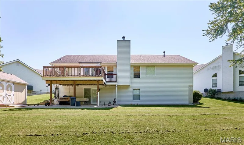 Spacious two-story residence with composite siding exterior, multiple chimneys, and a covered deck with wood railings — 3641 Wind Chime Lane, St Charles, MO 63301