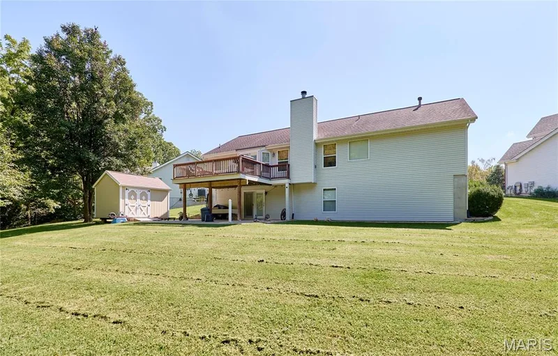 Spacious two-story residence with light-colored exterior siding, metal chimney, and covered rear deck — 3641 Wind Chime Lane, St Charles, MO 63301