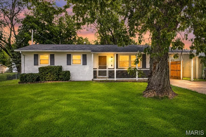 White siding exterior with dark shutters, covered front entry, established tree, and a paved driveway — 11 Toelle Drive, St Charles, MO 63304