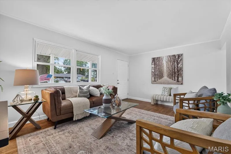 Spacious living area featuring expansive windows, wood-finish flooring, and crown molding — 11 Toelle Drive, St Charles, MO 63304