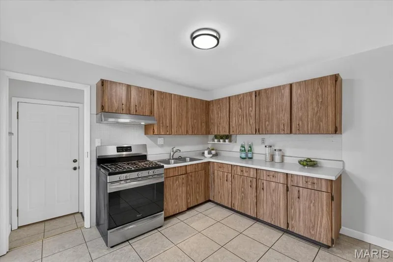 Kitchen featuring wood-finish cabinetry, stainless steel range, white countertops, and tiled flooring — 11 Toelle Drive, St Charles, MO 63304