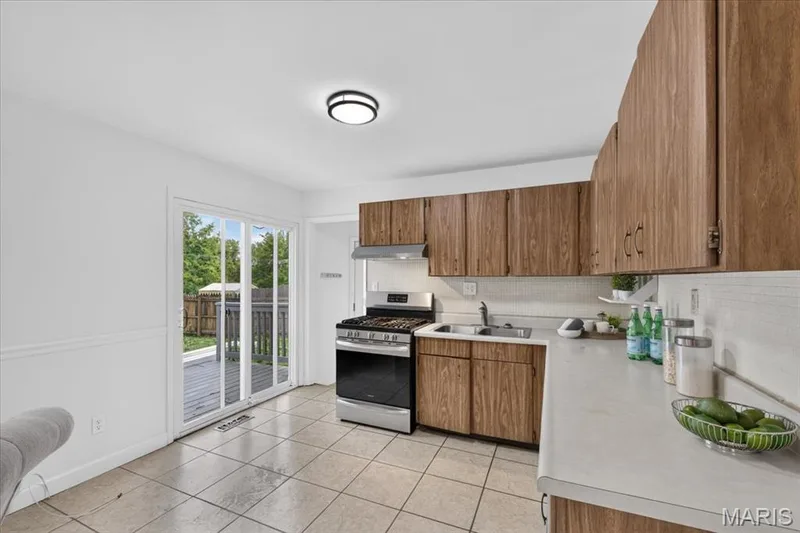 Kitchen featuring wood-finish cabinetry, light-toned countertops, and a tiled backsplash — 11 Toelle Drive, St Charles, MO 63304