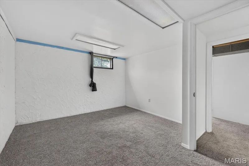 Carpeted room with white textured walls and a ceiling-mounted fluorescent light fixture — 11 Toelle Drive, St Charles, MO 63304