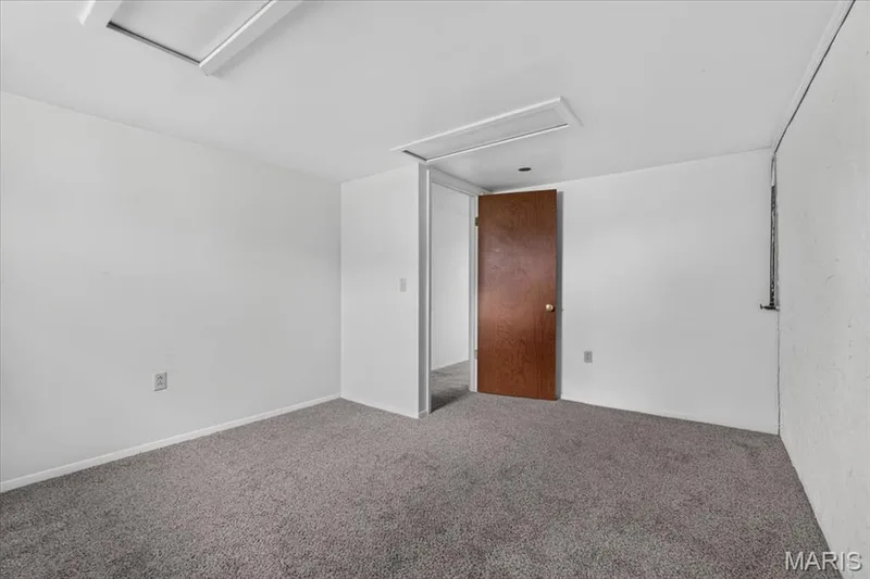 Neutral-toned carpeting with white walls and a warm wood-toned door — 11 Toelle Drive, St Charles, MO 63304