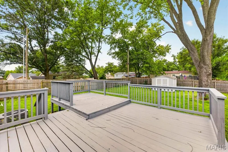 Multi-level wood deck with painted railings, overlooking a fenced yard with mature trees and a detached storage shed — 11 Toelle Drive, St Charles, MO 63304