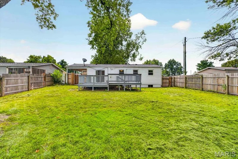 Expansive backyard featuring a large grassy area, wood privacy fencing, and a raised wood deck — 11 Toelle Drive, St Charles, MO 63304