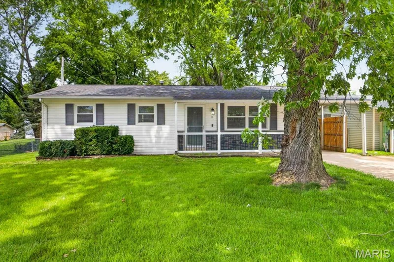 White siding exterior with grey shutters, covered front porch, and mature landscaping — 11 Toelle Drive, St Charles, MO 63304