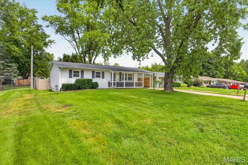 White siding exterior with dark shutters, covered front entry, and a mature tree providing shade — 11 Toelle Drive, St Charles, MO 63304