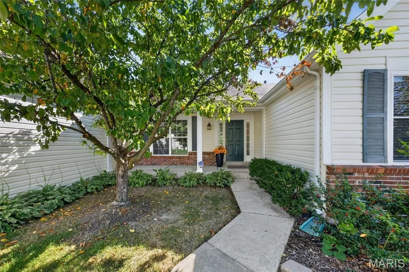 Inviting front entry with a dark green door, covered porch, and white column — 155 Snake River Drive, Dardenne Prairie, MO 63368