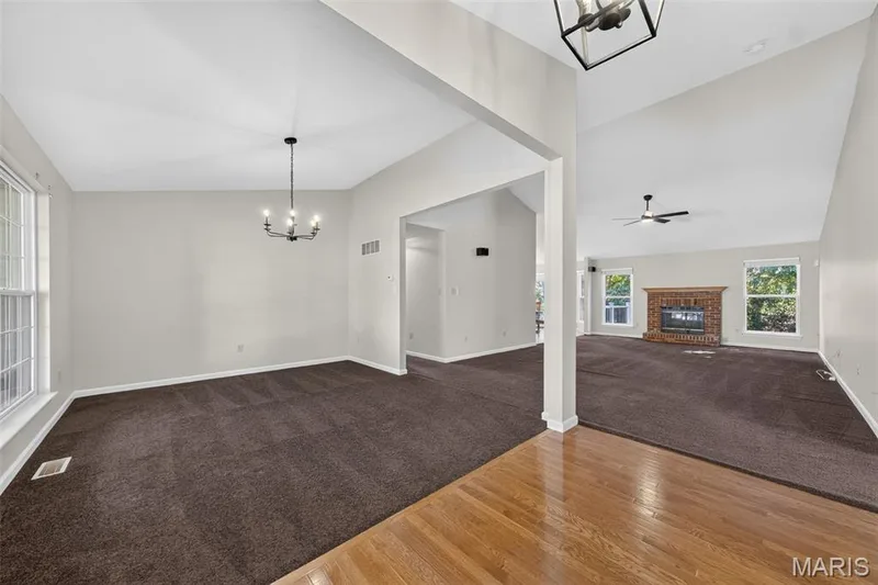 Hardwood flooring entrance leading to a carpeted living area with a vaulted ceiling and exposed beam — 155 Snake River Drive, Dardenne Prairie, MO 63368