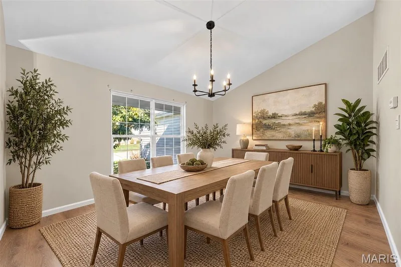 Vaulted ceiling with a black chandelier, wood-finish flooring, white window trim, and a neutral wall color — 155 Snake River Drive, Dardenne Prairie, MO 63368