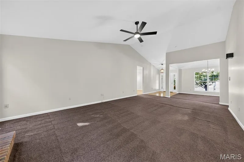 Vaulted ceiling with a ceiling fan, wall-to-wall carpeting, and a brick fireplace hearth — 155 Snake River Drive, Dardenne Prairie, MO 63368