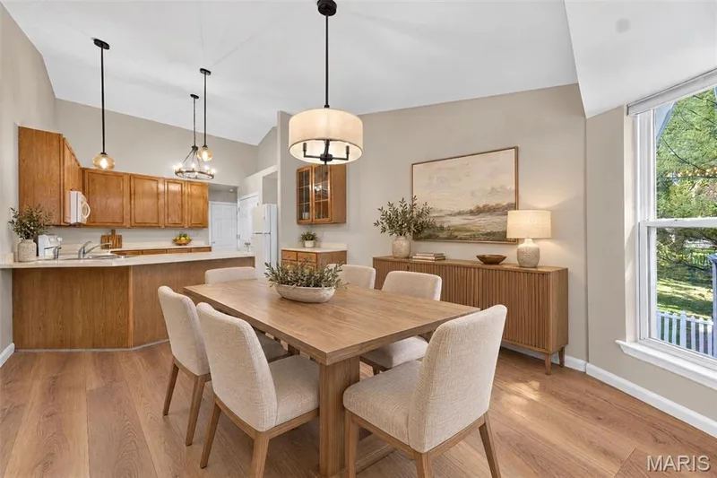 Vaulted ceiling with pendant lighting, wood-finish flooring, kitchen cabinetry, and a large window — 155 Snake River Drive, Dardenne Prairie, MO 63368