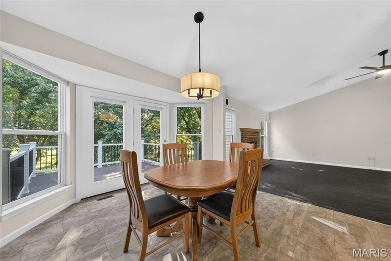 Dining area featuring large windows, double glass doors, a decorative light fixture, and tile flooring — 155 Snake River Drive, Dardenne Prairie, MO 63368