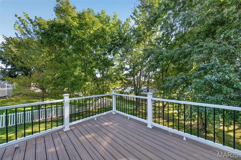 Composite deck with white railings and black balusters, surrounded by mature trees — 155 Snake River Drive, Dardenne Prairie, MO 63368