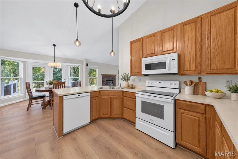 Vaulted ceilings, wood-finish flooring, white appliances, wood cabinetry, and a dining area with multiple windows — 155 Snake River Drive, Dardenne Prairie, MO 63368
