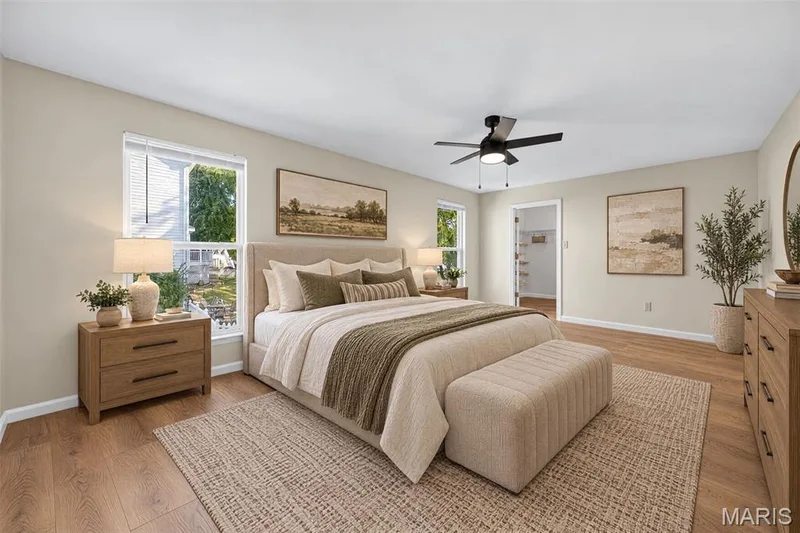 Wood-finish flooring, multiple windows providing natural light, ceiling fan with integrated lighting, and an open doorway leading to an additional space — 155 Snake River Drive, Dardenne Prairie, MO 63368