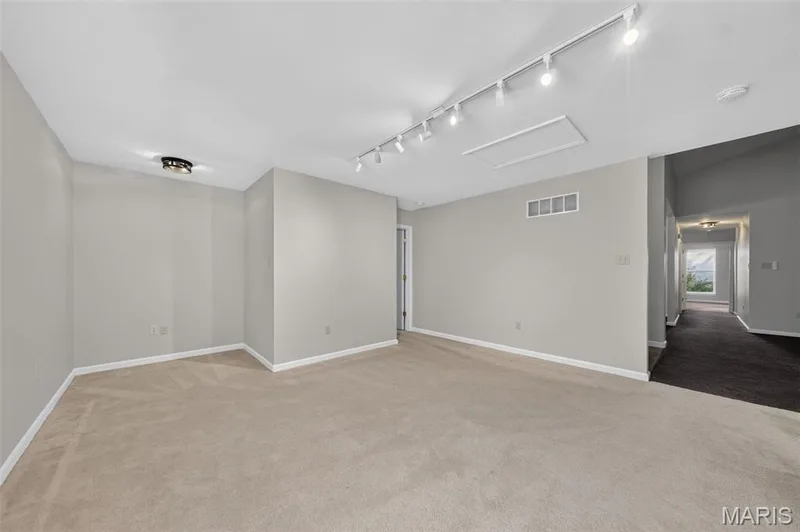 Expansive room featuring neutral-toned carpeting, track lighting, and a flush-mount ceiling fixture — 155 Snake River Drive, Dardenne Prairie, MO 63368