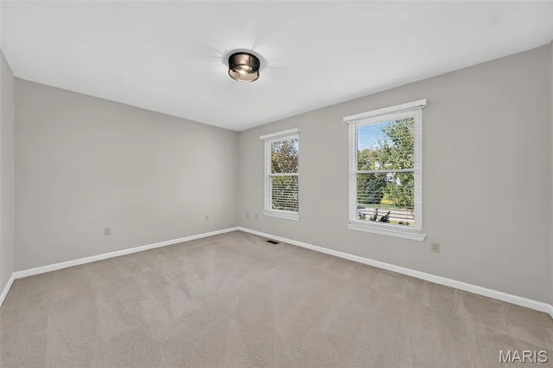 Carpeted room featuring light gray walls, two windows with blinds, and a semi-flush mount ceiling light — 155 Snake River Drive, Dardenne Prairie, MO 63368