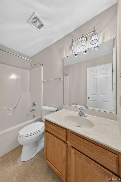Bathroom featuring a single vanity with wood-finish cabinetry, an integrated sink, and a large wall-mounted mirror — 155 Snake River Drive, Dardenne Prairie, MO 63368
