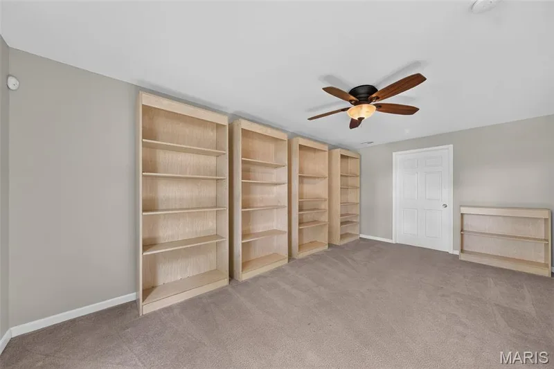 Built-in shelving, ceiling fan with integrated lighting, neutral carpet, and light-toned walls — 155 Snake River Drive, Dardenne Prairie, MO 63368