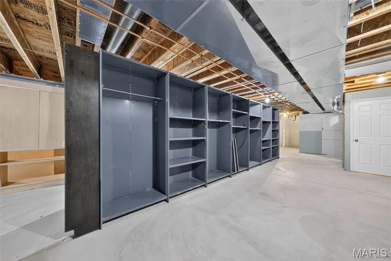 Extensive built-in storage units, wood-finish cabinetry, exposed wood ceiling joists, and a concrete floor — 155 Snake River Drive, Dardenne Prairie, MO 63368