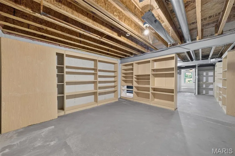 Unfinished basement space featuring substantial built-in shelving, exposed overhead joists and ductwork, and a concrete floor — 155 Snake River Drive, Dardenne Prairie, MO 63368