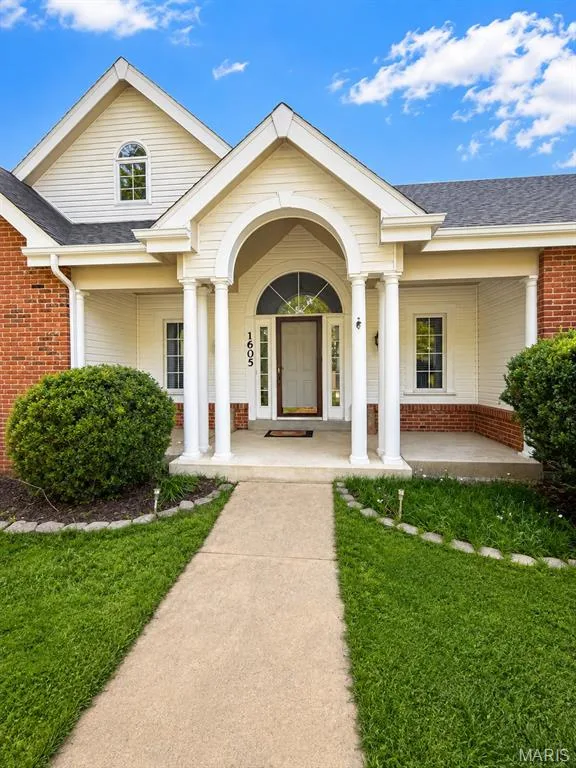 Brick and siding exterior with a covered front porch featuring white columns and an arched entry — 1605 Ridge Bend Drive, Glencoe, MO 63038