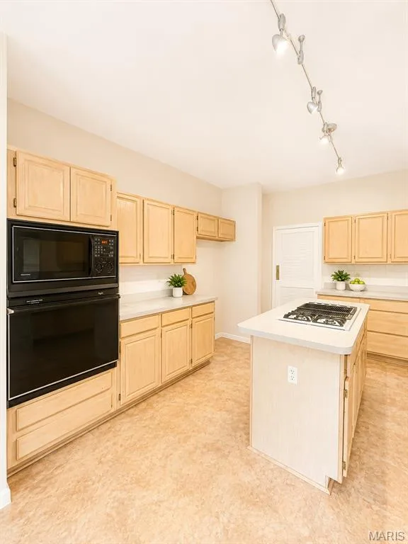 Kitchen featuring an integrated wall oven and microwave, a gas cooktop, light wood cabinetry, light-toned countertops, and track lighting — 1605 Ridge Bend Drive, Glencoe, MO 63038