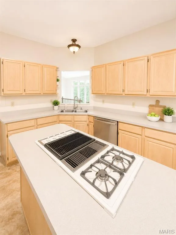 Chef's kitchen featuring natural wood cabinetry, white quartz countertops, a stainless steel cooktop with gas burners and griddle, and a center island with seating — 1605 Ridge Bend Drive, Glencoe, MO 63038