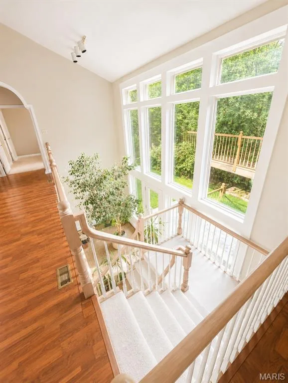 Wall of windows, wood-finish flooring, and a carpeted staircase with wood handrails — 1605 Ridge Bend Drive, Glencoe, MO 63038