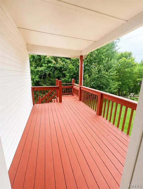 Expansive composite deck featuring rich red-stained wood flooring, aluminum railings with balusters, and a covered overhead structure — 1605 Ridge Bend Drive, Glencoe, MO 63038