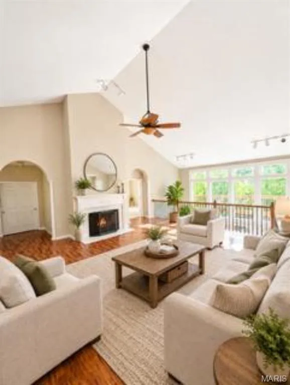 Vaulted ceiling with a ceiling fan, fireplace with a white mantel, wood-finish flooring, and arched doorways, virtually staged — 1605 Ridge Bend Drive, Glencoe, MO 63038