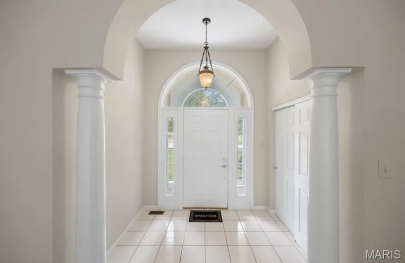 Arched entryway with decorative columns, transom window over the main door, and white tile flooring — 1605 Ridge Bend Drive, Glencoe, MO 63038