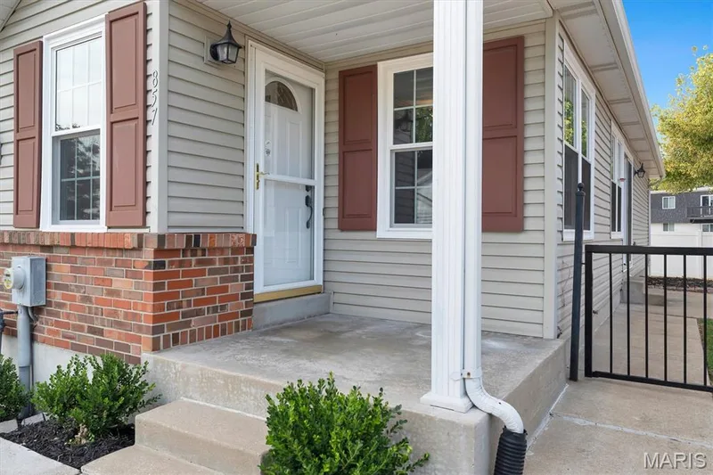 Brick and siding exterior with concrete porch, white entry door with screen, and dark red decorative shutters — 857 Du Pre Court, St Peters, MO 63376