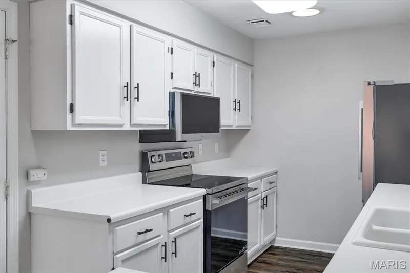 White cabinetry with black hardware, white countertops, stainless steel range, and wood-finish flooring — 857 Du Pre Court, St Peters, MO 63376