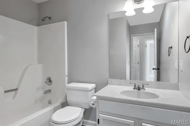 Bathroom featuring a white vanity with an integrated sink, polished chrome faucet, a wall-mounted mirror, and a white tub and shower combination — 857 Du Pre Court, St Peters, MO 63376