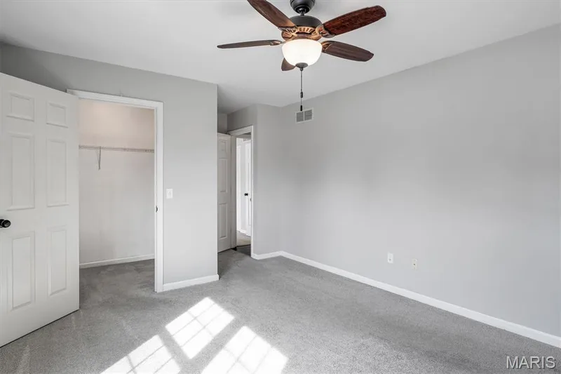 Carpeted flooring, light gray wall finishes, overhead ceiling fan with integrated lighting, and a closet with shelving — 857 Du Pre Court, St Peters, MO 63376