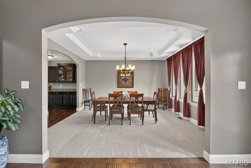 Dining area with tray ceiling, chandelier, wall-to-wall carpeting, and floor-to-ceiling window treatments — 1307 Homestead Heights Drive, Wildwood, MO 63005