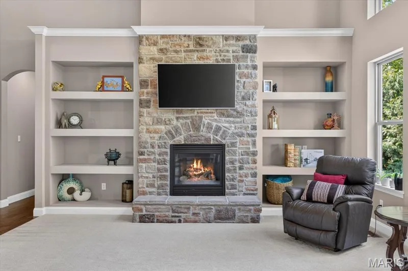 Stone fireplace with hearth, integrated built-in shelving and crown molding — 1307 Homestead Heights Drive, Wildwood, MO 63005