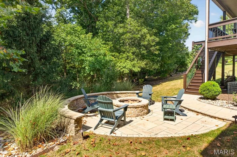 Stone patio with a built-in fire pit, stone retaining wall, and landscaped planting beds — 1307 Homestead Heights Drive, Wildwood, MO 63005