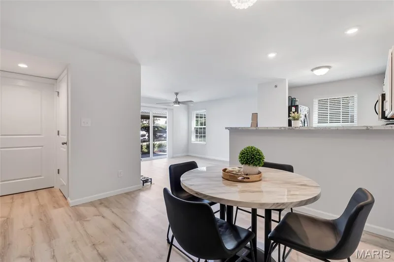 Bright, open-concept dining area with brand new luxury vinyl plank flooring, leading seamlessly into the main living space and kitchen breakfast bar. — 4101 Spring Creek Lane, O'Fallon, MO 63368