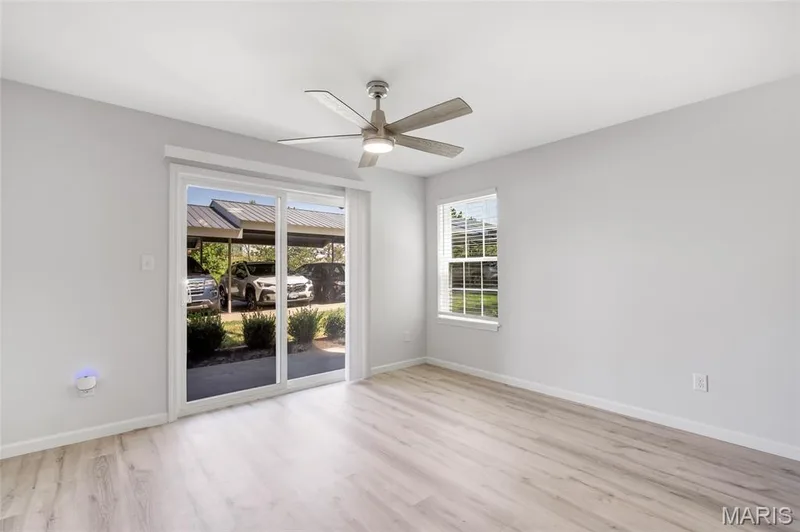 Sunlit living room featuring crisp neutral walls and soft natural light draw your gaze toward the private patio through the sliding glass doors. — 4101 Spring Creek Lane, O'Fallon, MO 63368