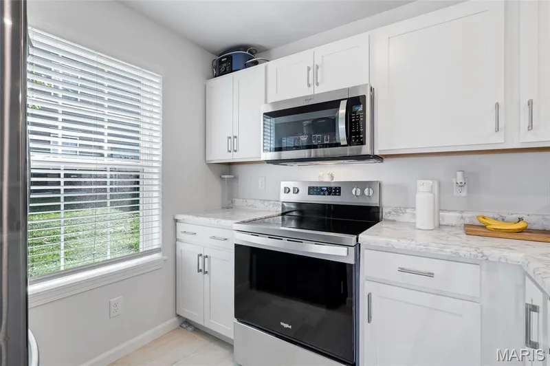 Completely updated kitchen outfitted with bright white cabinetry and modern stainless steel appliances. — 4101 Spring Creek Lane, O'Fallon, MO 63368