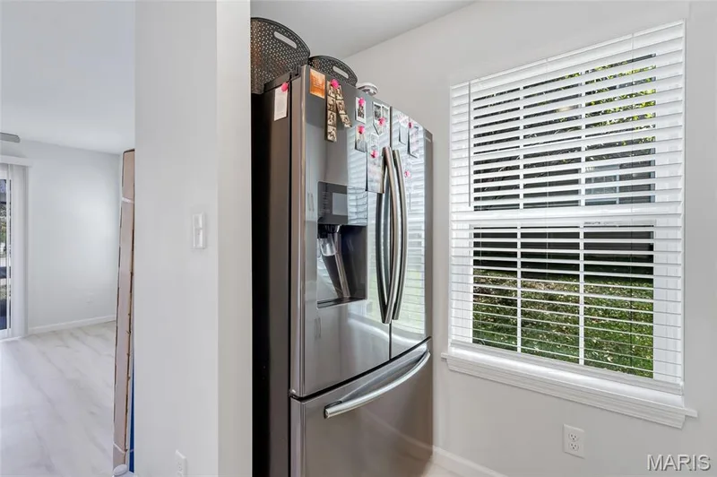 Convenient kitchen nook with generous natural lighting from large windows, complete with a full-size stainless steel refrigerator. — 4101 Spring Creek Lane, O'Fallon, MO 63368